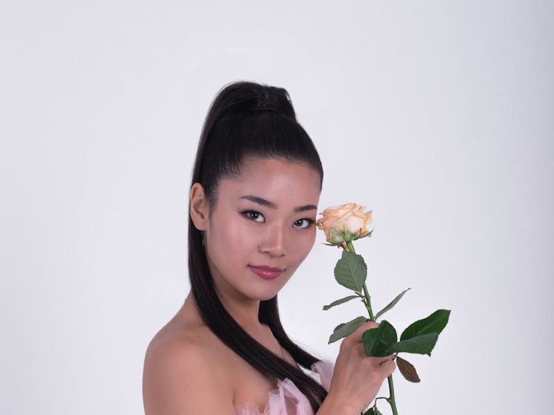 A wide shot of a person in a dynamic but controlled movement pose in a minimalist studio.